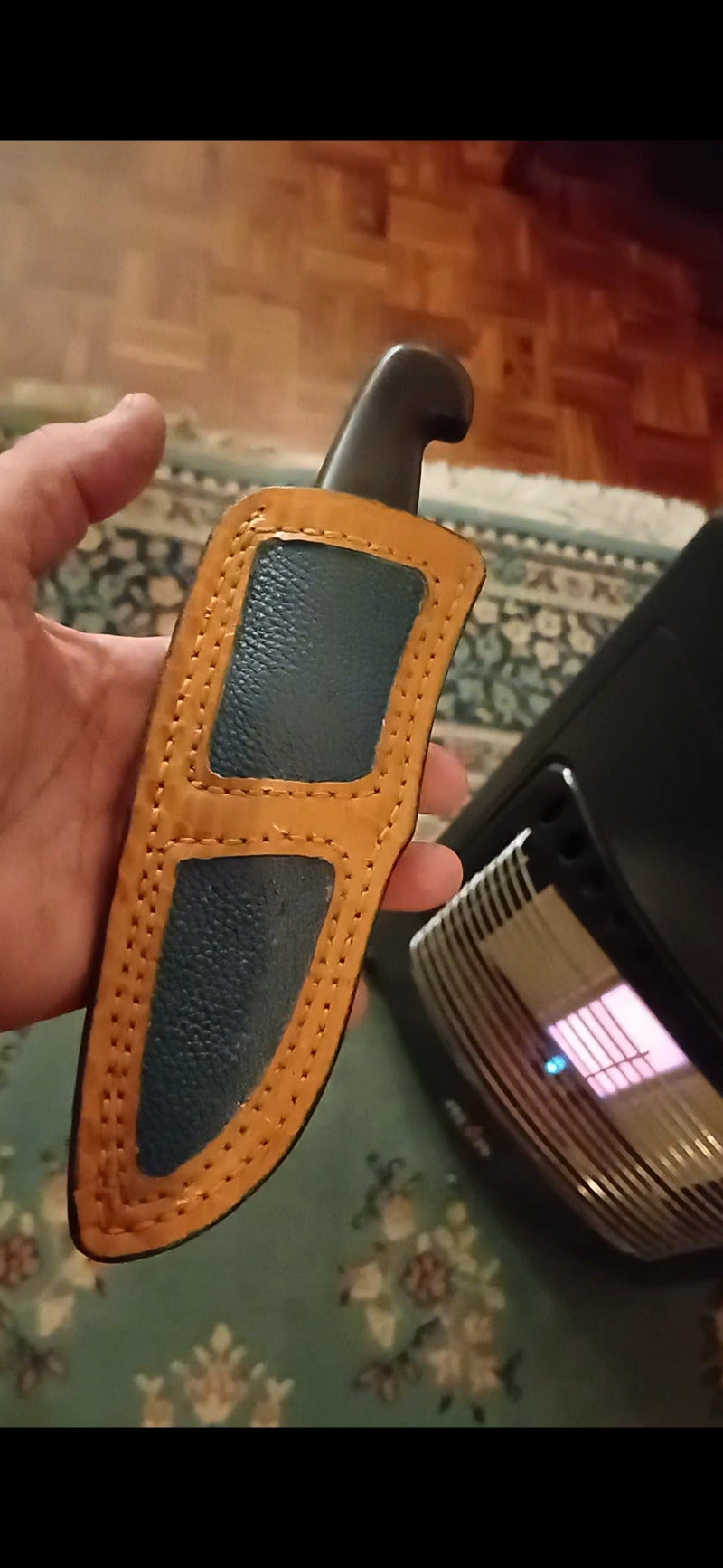 Holding a brown leather knife sheath with a blurred background